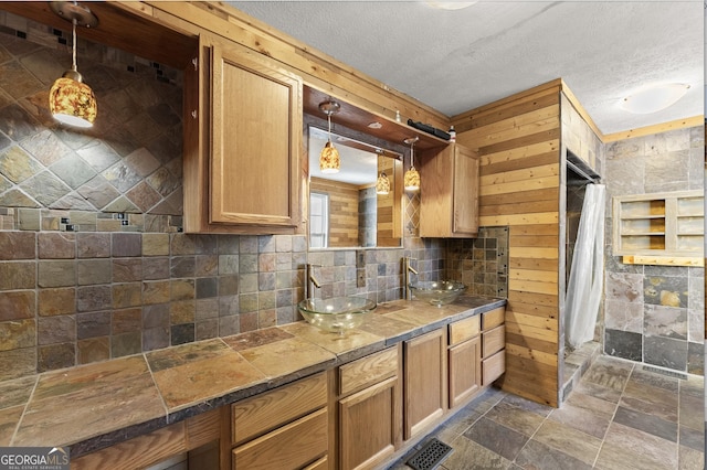 kitchen with a textured ceiling, wood walls, and sink