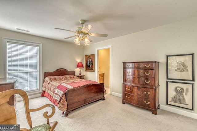 bedroom with ceiling fan, ensuite bathroom, light carpet, and multiple windows