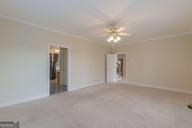 carpeted spare room with ceiling fan and ornamental molding