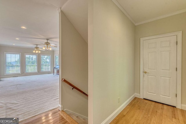 staircase with ceiling fan, wood-type flooring, and ornamental molding