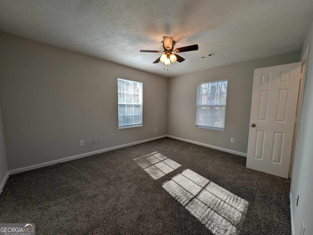 empty room with ceiling fan, dark carpet, and a textured ceiling