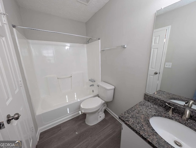 full bathroom with bathing tub / shower combination, wood-type flooring, a textured ceiling, toilet, and vanity