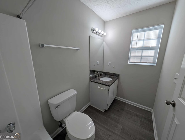 bathroom with toilet, vanity, a textured ceiling, and hardwood / wood-style flooring