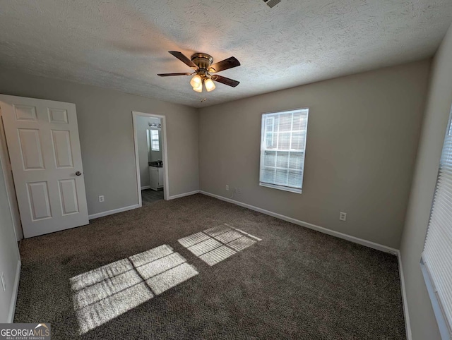 unfurnished bedroom with ceiling fan, ensuite bathroom, dark carpet, and a textured ceiling