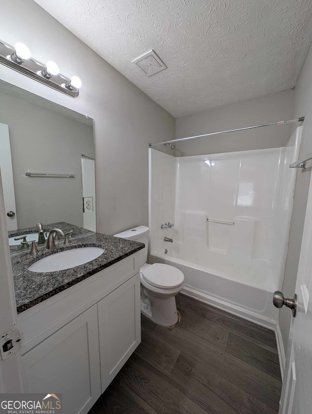 full bathroom with vanity, a textured ceiling, shower / tub combination, hardwood / wood-style flooring, and toilet