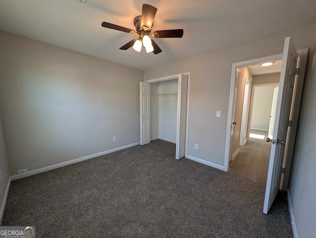 unfurnished bedroom with a textured ceiling, a closet, dark carpet, and ceiling fan