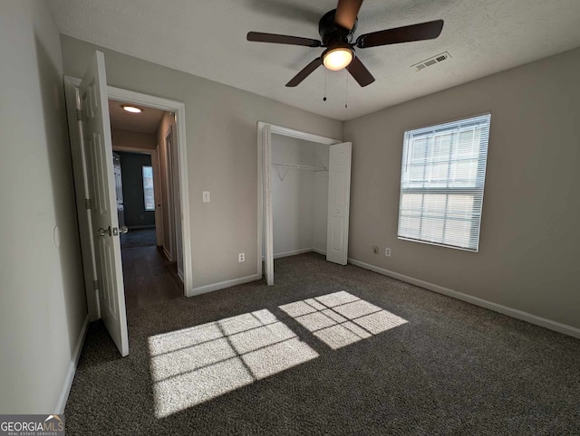 unfurnished bedroom featuring ceiling fan, a closet, and dark colored carpet