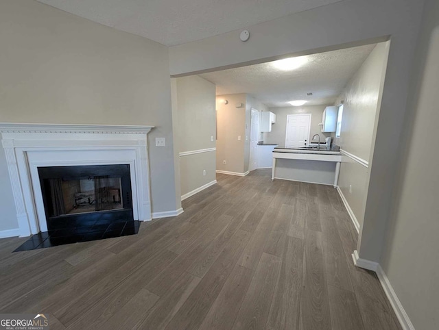 unfurnished living room featuring hardwood / wood-style floors, sink, and a textured ceiling