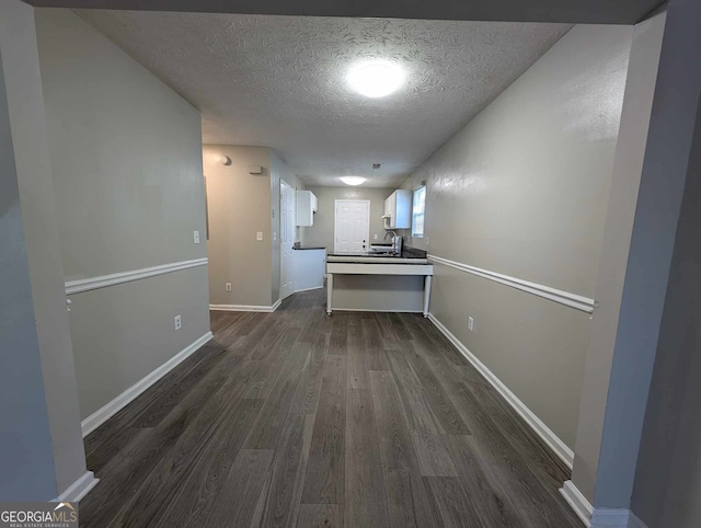 hallway with dark hardwood / wood-style floors and a textured ceiling