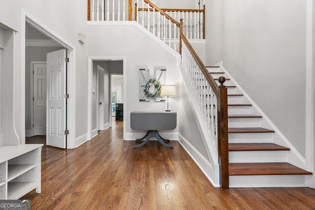 staircase with hardwood / wood-style floors, ornamental molding, and a high ceiling