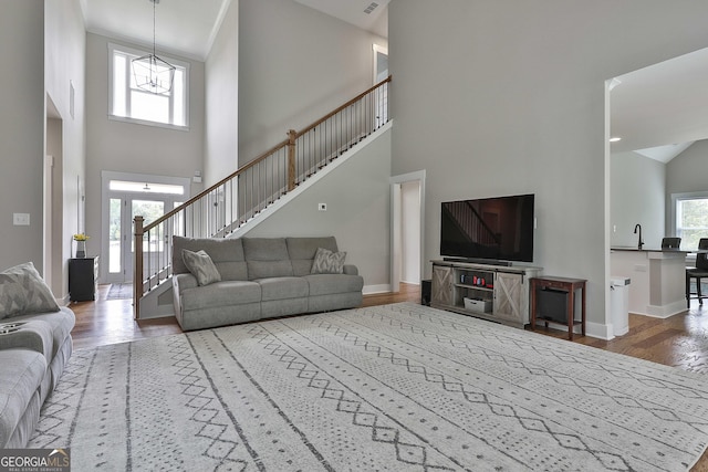 living room featuring a high ceiling, sink, a healthy amount of sunlight, and hardwood / wood-style floors