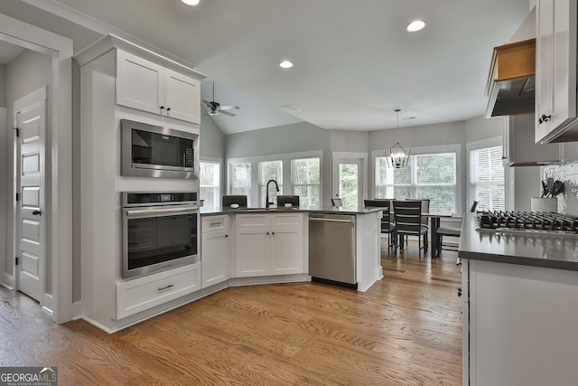 kitchen with white cabinets, hanging light fixtures, light wood-type flooring, and appliances with stainless steel finishes