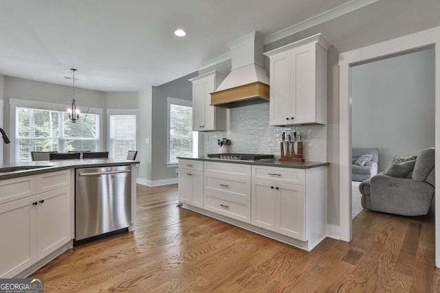 kitchen featuring appliances with stainless steel finishes, tasteful backsplash, custom exhaust hood, decorative light fixtures, and white cabinets