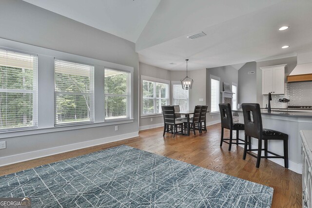 dining area featuring a chandelier, dark hardwood / wood-style floors, vaulted ceiling, and sink