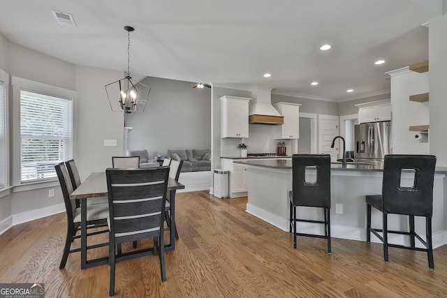 kitchen with pendant lighting, white cabinetry, premium range hood, and light hardwood / wood-style flooring