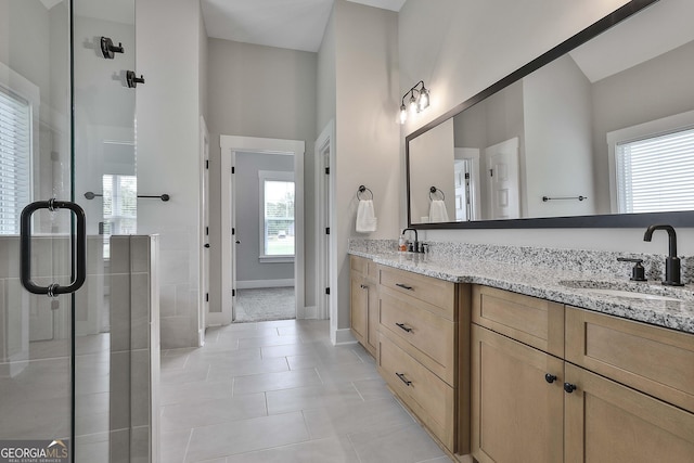 bathroom with a wealth of natural light, a shower with door, vanity, and tile patterned flooring