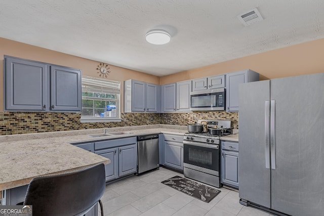 kitchen featuring backsplash, sink, light tile patterned floors, and stainless steel appliances