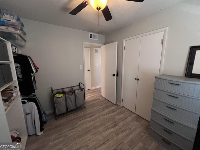 interior space featuring hardwood / wood-style flooring, ceiling fan, a textured ceiling, and a closet