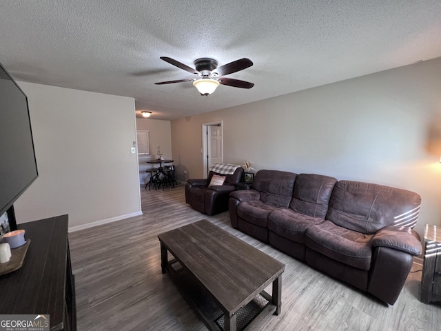 living room with ceiling fan, wood-type flooring, and a textured ceiling