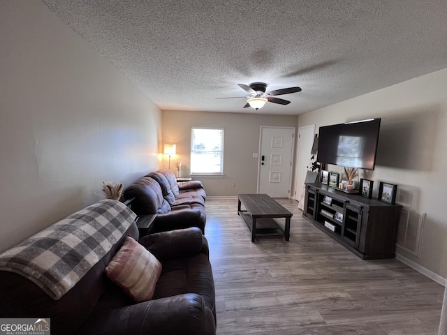 living room with ceiling fan, hardwood / wood-style floors, and a textured ceiling