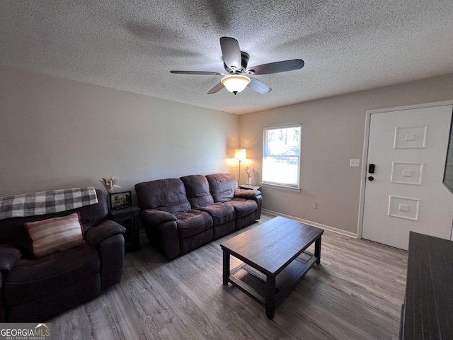 living room featuring ceiling fan, light hardwood / wood-style floors, and a textured ceiling