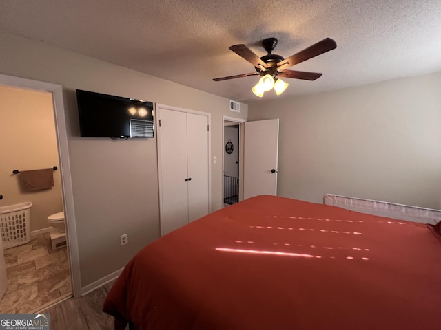 bedroom with ensuite bathroom, a textured ceiling, ceiling fan, wood-type flooring, and a closet