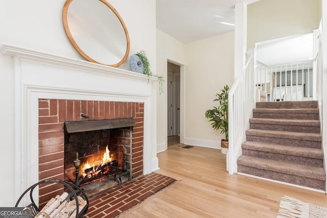 interior space with wood-type flooring and a brick fireplace