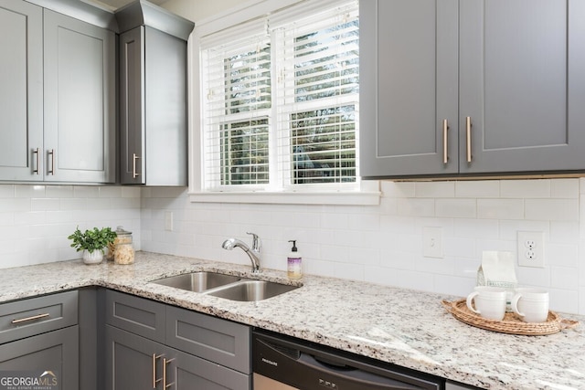 kitchen with light stone countertops, tasteful backsplash, gray cabinetry, sink, and dishwasher