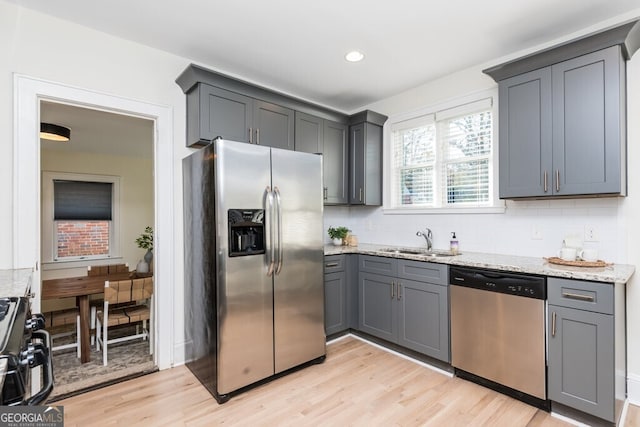 kitchen with light stone countertops, appliances with stainless steel finishes, gray cabinets, and sink