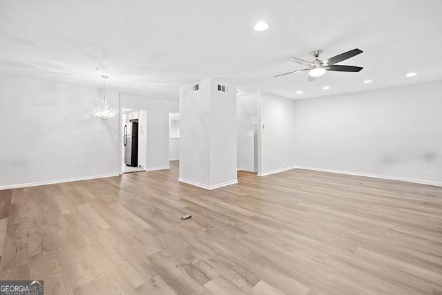 unfurnished living room featuring ceiling fan with notable chandelier and light hardwood / wood-style flooring