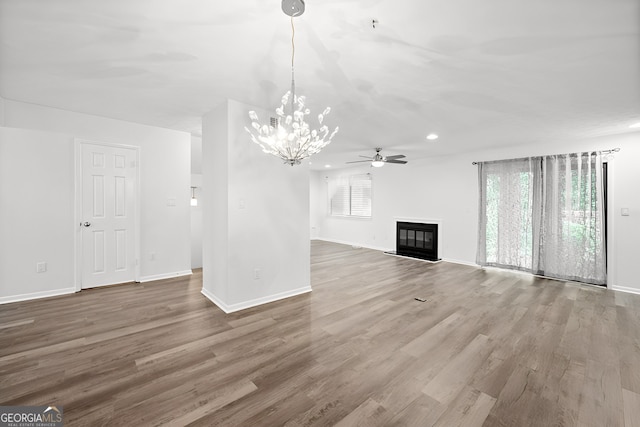 unfurnished living room featuring hardwood / wood-style flooring and ceiling fan with notable chandelier