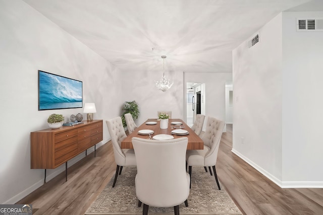 dining area featuring a notable chandelier and light wood-type flooring