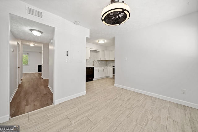 interior space featuring sink, light hardwood / wood-style floors, and a textured ceiling