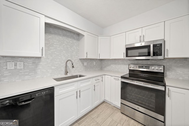 kitchen featuring appliances with stainless steel finishes, sink, white cabinets, and decorative backsplash