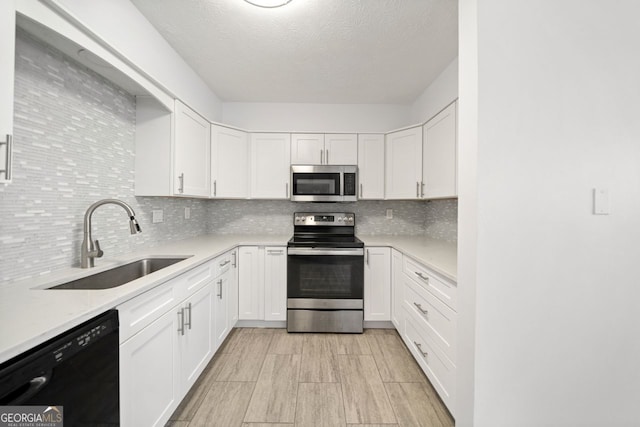 kitchen with appliances with stainless steel finishes, light stone countertops, sink, and white cabinets