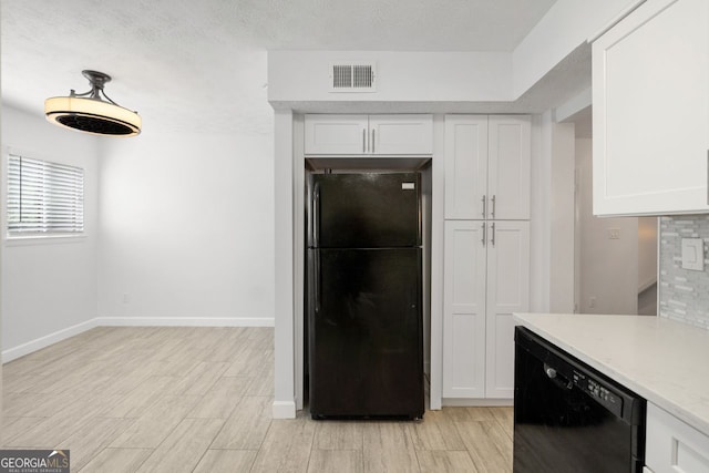 kitchen with light stone counters, white cabinets, light wood-type flooring, and black appliances