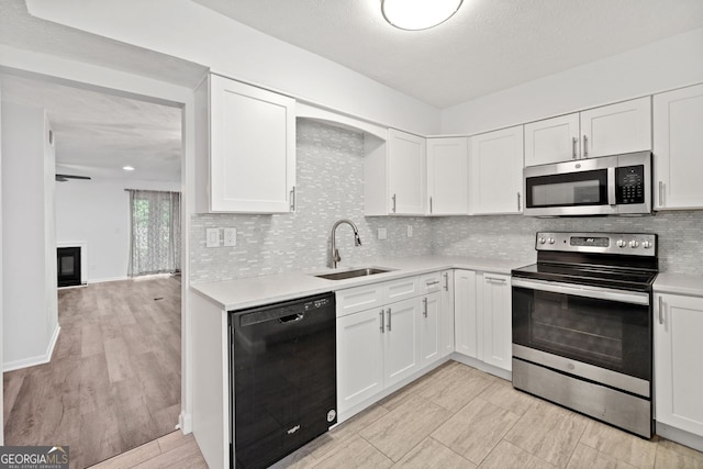 kitchen featuring white cabinetry, sink, decorative backsplash, light hardwood / wood-style floors, and stainless steel appliances