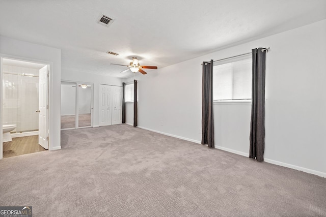 unfurnished bedroom featuring ceiling fan, ensuite bathroom, and light carpet