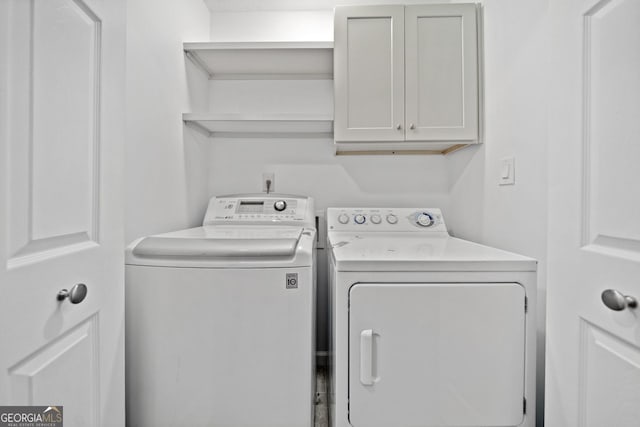 clothes washing area featuring cabinets and washer and clothes dryer