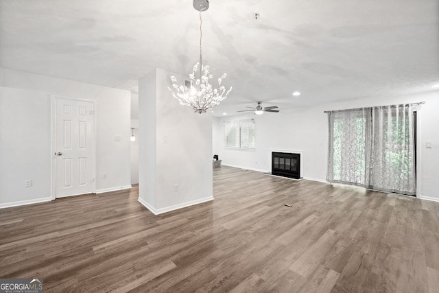 unfurnished living room featuring ceiling fan with notable chandelier and wood-type flooring