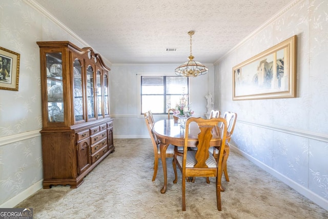 carpeted dining space with ornamental molding, a textured ceiling, and an inviting chandelier