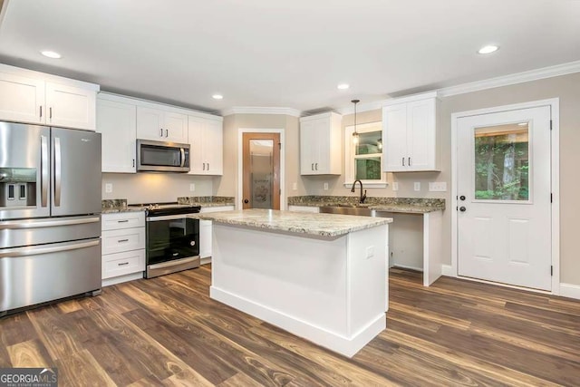 kitchen with appliances with stainless steel finishes, sink, decorative light fixtures, white cabinets, and a center island