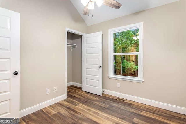 unfurnished bedroom featuring ceiling fan, a closet, dark wood-type flooring, and vaulted ceiling