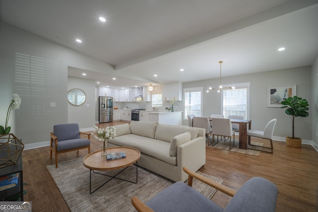 living room featuring an inviting chandelier, lofted ceiling with beams, and hardwood / wood-style flooring