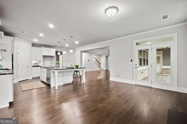 kitchen with pendant lighting, sink, white cabinets, a kitchen island with sink, and stainless steel dishwasher