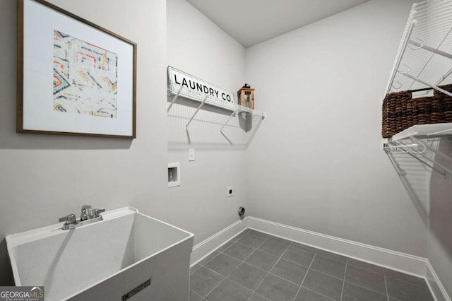 laundry area with electric dryer hookup, hookup for a washing machine, sink, and dark tile patterned floors