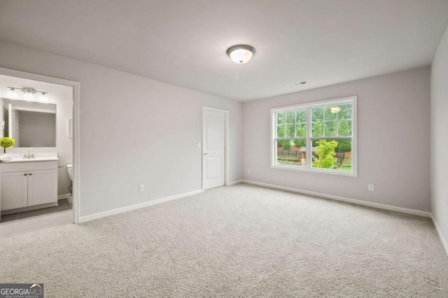 unfurnished bedroom featuring connected bathroom, sink, and light colored carpet