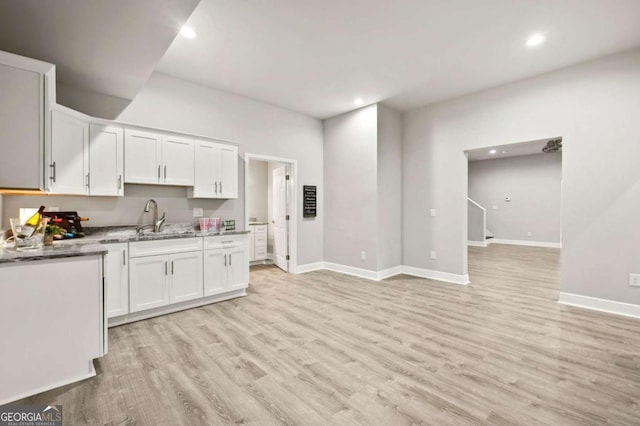 kitchen featuring light wood-type flooring, sink, light stone counters, and white cabinets