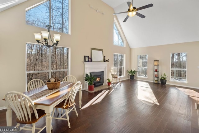 dining area with dark hardwood / wood-style floors, ceiling fan with notable chandelier, and high vaulted ceiling