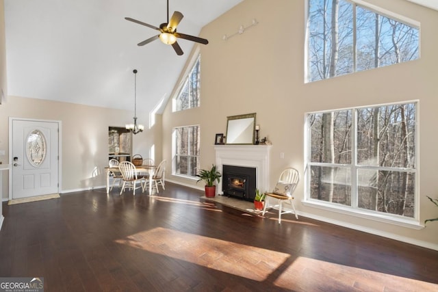 living room with ceiling fan with notable chandelier, hardwood / wood-style flooring, and high vaulted ceiling